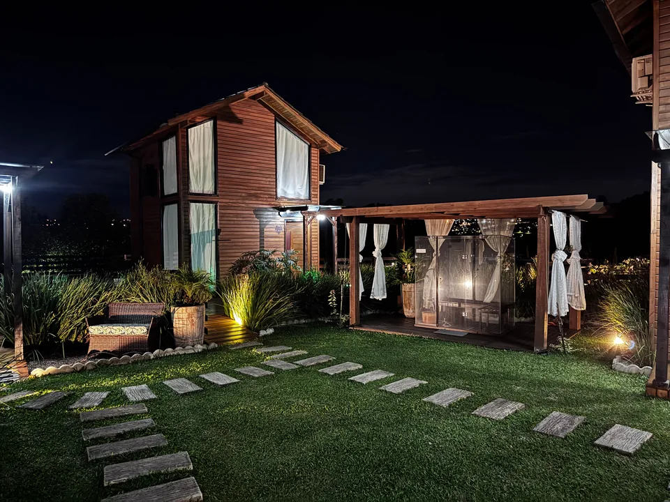 As cabanas iluminadas à noite, com o caminho de pedras aceso no gramado