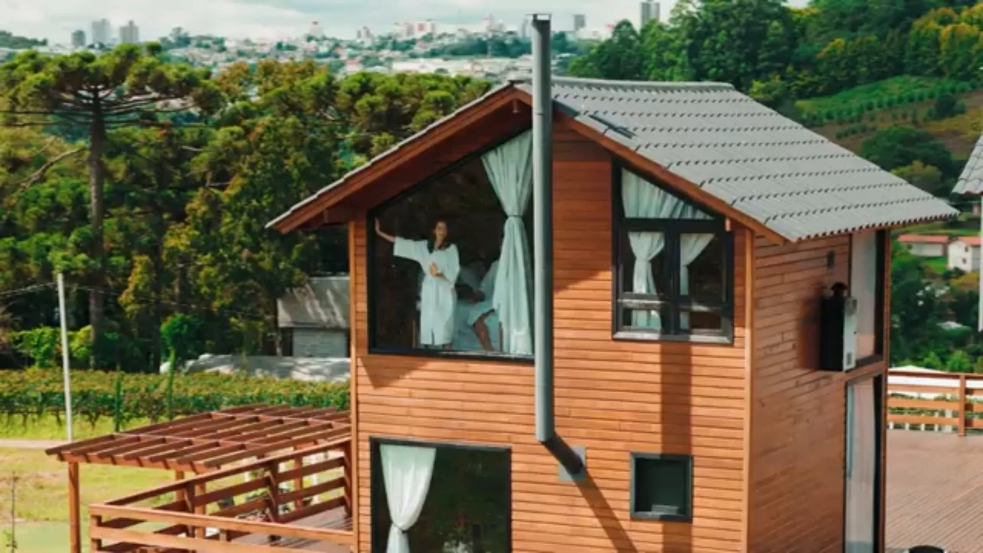 Cabana de madeira da Capanna del Vale vista do alto, com o parreiral ao lado e o vale ao fundo